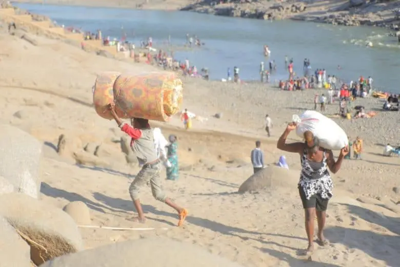 Ethiopian refugees holding their belongings.