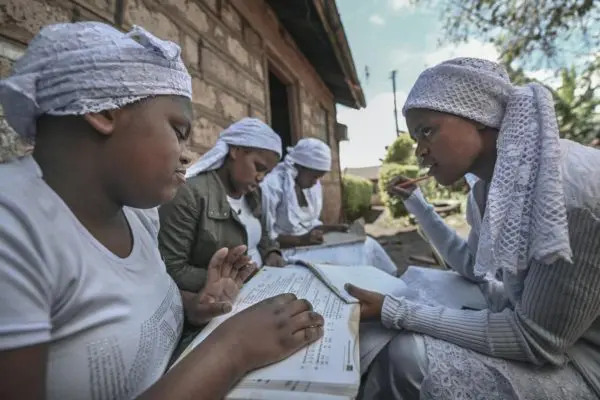 Stateless Shona woman Nosizi Reuben Dube (right) assists her sisters, (from left) Janet, Tema and Brenda, with their studies, outside their home in Kinoo, Kenya.