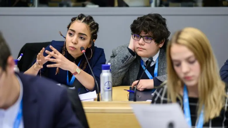 Model UN delegates speaking into a micropone.