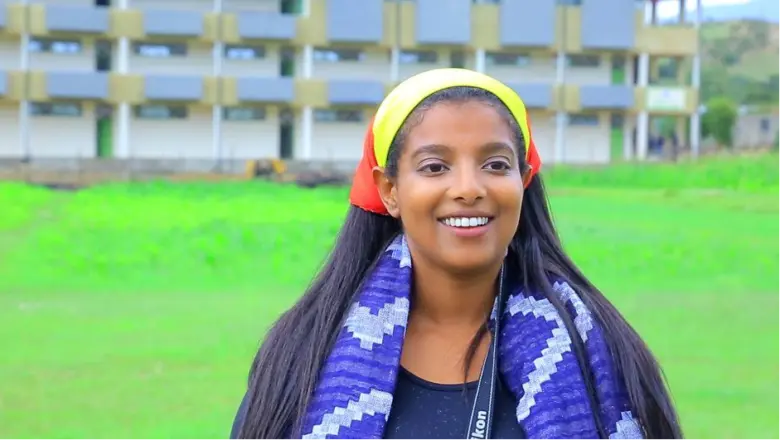 Yohana smiles in an outdoor parc.