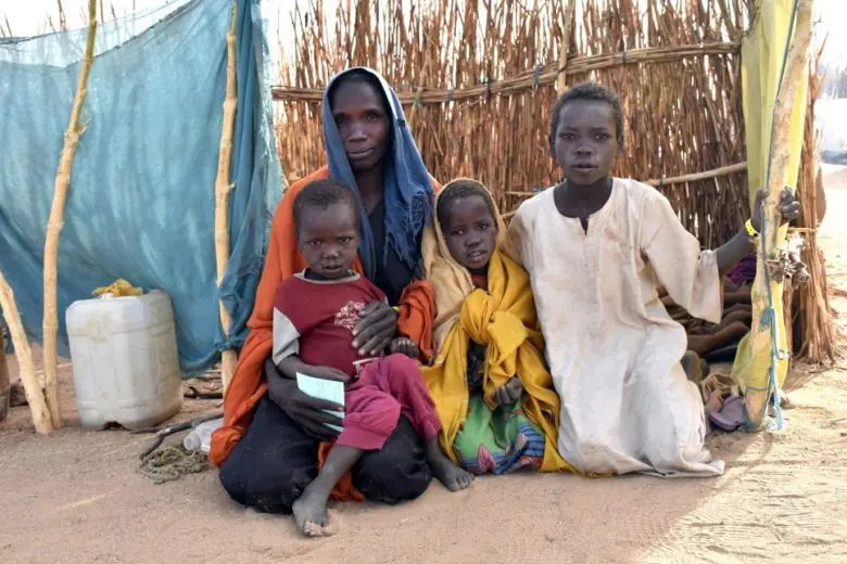 Des réfugiés soudanais sont assis auprès de leur abri de fortune à Hilouta, au Tchad. 