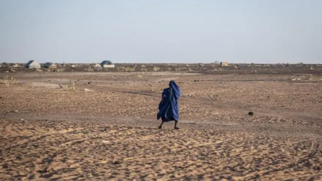 A man walks across arid land near Kaya, Burkina Faso.