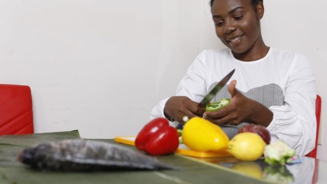 Refugee Anuarite Manyoha, from the Democratic Republic of the Congo, chops peppers.