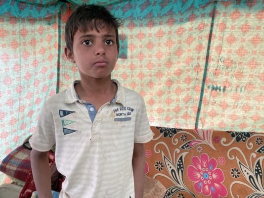 A 12-year-old displaced Yemeni boy stands inside a tent.