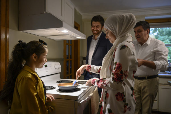 Taghrid Hadhad, la deuxième à partir de la droite, fait chauffer une poêle pour préparer un dessert appelé Nid de rossignol (ÔIsh El Bulbul) en suivant les conseils de son père Isam Hadhad, à droite, tandis que sa sœur Sana Alkadri, à gauche, et son frère Tareq Hadhad la regardent chez eux à Antigonish.