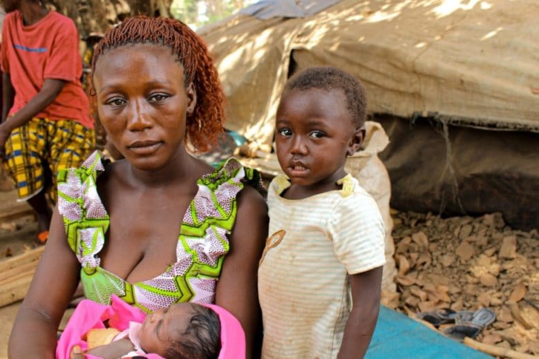 A refugee mother from Central African Republic sits with her children beside a makeshift shelter in Ndu village, the Democratic Republic of the Congo.