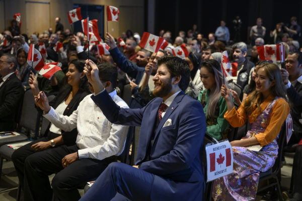 Tareq Hadhad, un réfugié syrien et le fondateur de Peace by Chocolate, agite un drapeau canadien avec 48 autres nouveaux Canadiens pendant sa cérémonie de citoyenneté canadienne.