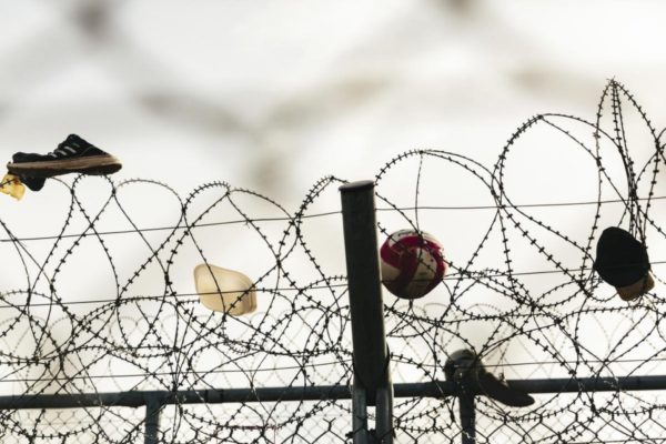 Shoes, a ball and a hat caught on a three layered barbed-wire fence.