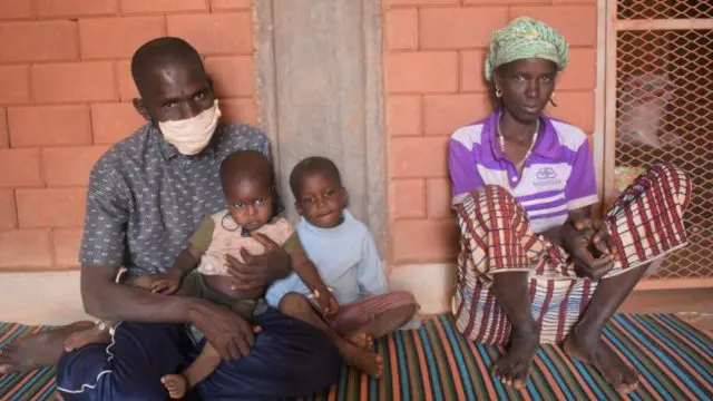 Une famille de 4 devant un mur de brique.