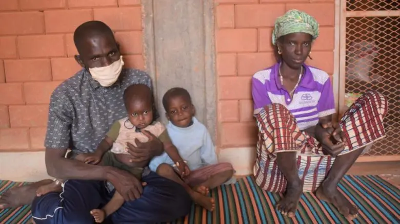 Une famille de 4 devant un mur de brique. 