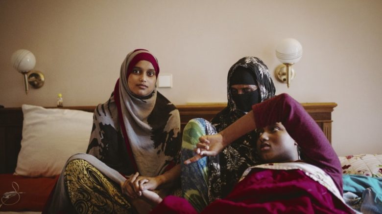 Une mère avec ses deux enfants dans une chambre d'hotel.
