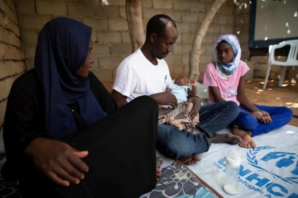 Sudanese refugees from Darfur sit with their newborn baby girl at home.