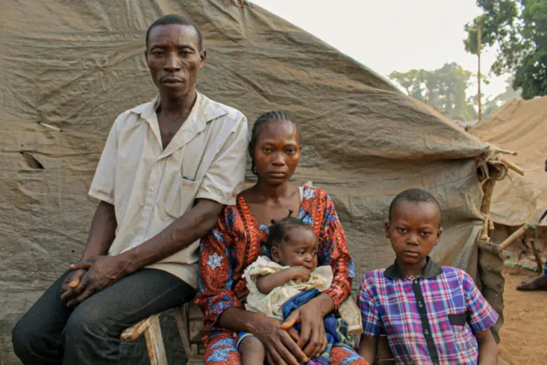 Family poses in front of a makeshift shelter.