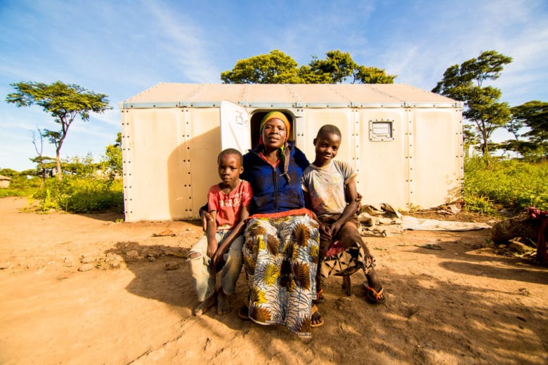 A women and her children pose outside their home in Kigoma Refugee Camp.