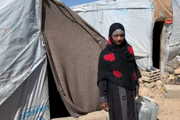 Woman stands in front of a tent.