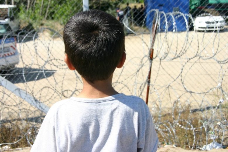 Child standing in front of a fence.