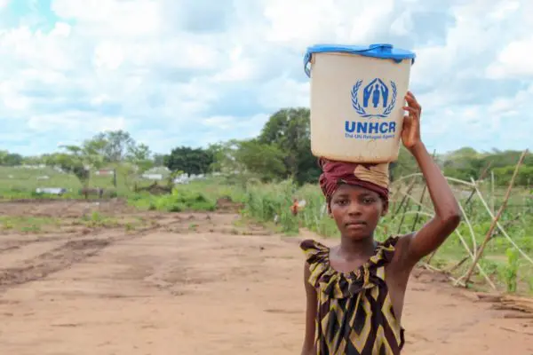 Adelia, 11, poses with a UNHCR branded container.