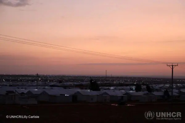 The sun sets over Azraq camp in Jordan and children gather to play football. ; Azraq is home to 36,000 Syrian refugees, of whom 60 per cent are children, including more than 120 unaccompanied and separated minors. Azraq refugee camp opened in April 2014 and camp management is co-coordinated by the Syrian Refugee Affairs Directorate (SRAD) and UNHCR. The village-based approach aims to foster a greater sense of ownership and community among residents. Jordan currently hosts some 750,000 refugees – the vast majority are Syrians fleeing persecution, conflict and violence in their home country, and many of them have been in exile for years with the conflict in Syria now entering its ninth year. More than 80 percent of all refugees in Jordan live out of camp in urban areas.
