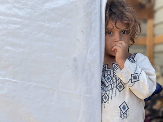Yemeni girl stands at the door of the makeshift shelter.