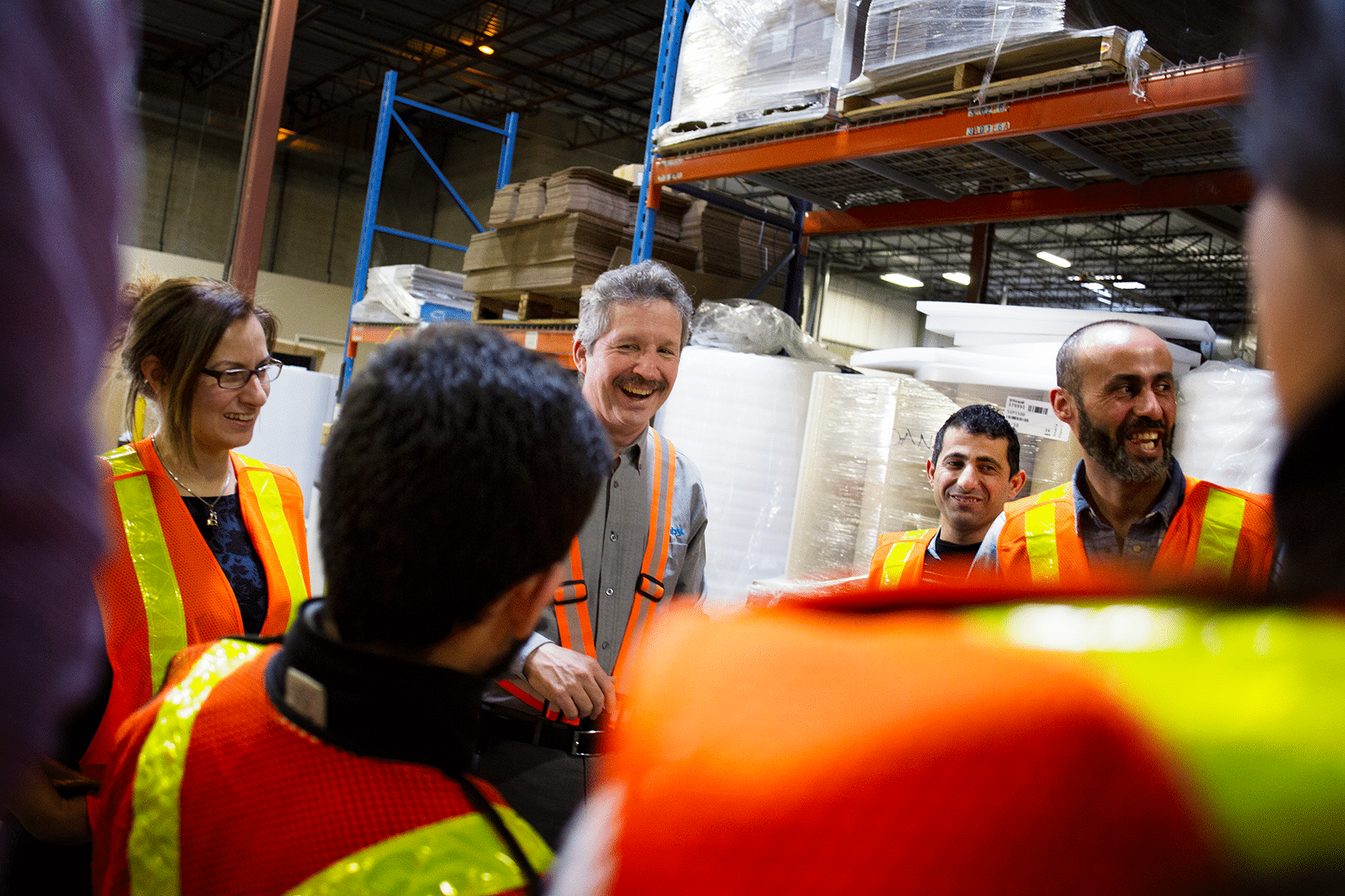 Jim Estill speaks with employees in a warehouse.