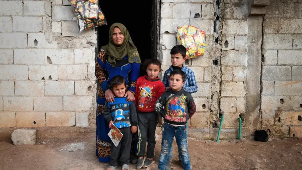 Abiha, 30 ans, se tient devant sa maison avec ses enfants à Dayr Hafir, en Syrie.