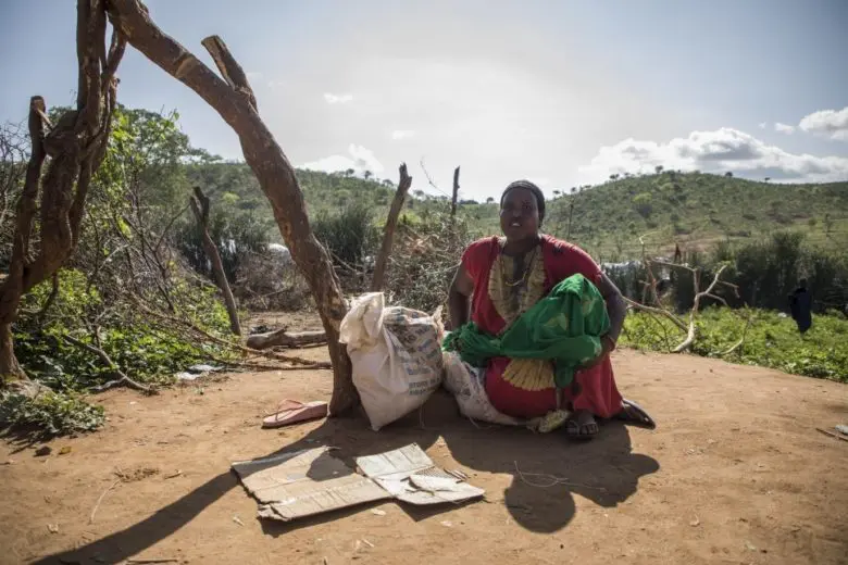 A woman is seated next to a bag of rice.