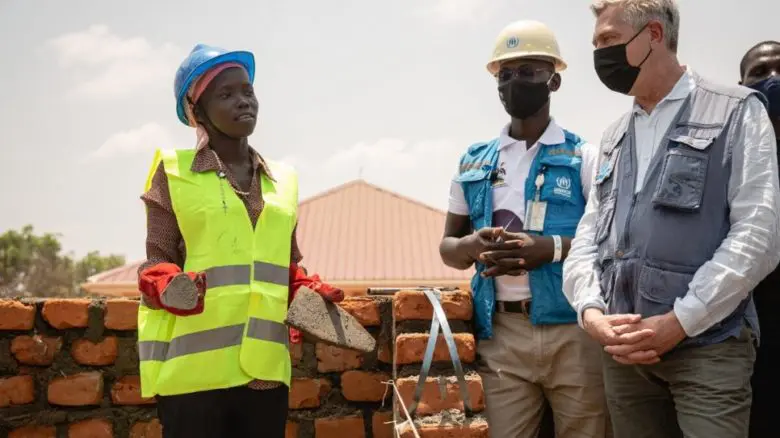 Two construction workers and the UNHCR High Commissioner.