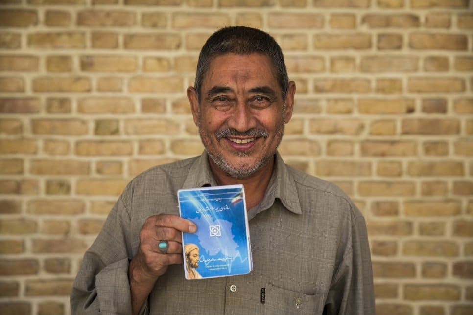 Le réfugié afghan Abdulrahim Rostami, 66 ans, tient en main son carnet d’assurance-maladie à Téhéran, en Iran. 