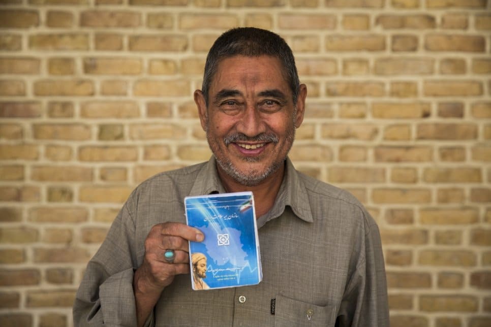 Afghan refugee Abdulrahim Rostami, 66, holds his health insurance booklet in Tehran, Iran.