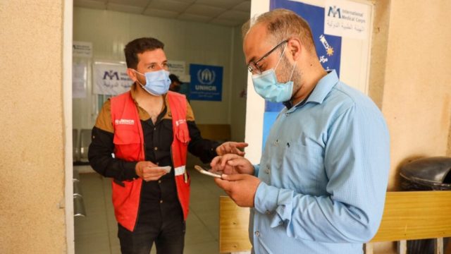 Samih, 32 ans, aide un autre réfugié du camp à s’inscrire pour recevoir le vaccin contre le Covid-19.