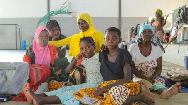 Maria (en jaune) avec ses filles et d'autres proches dans un centre de transit à Pemba.