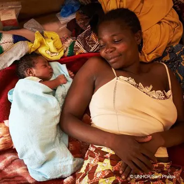 Woman lies with baby.