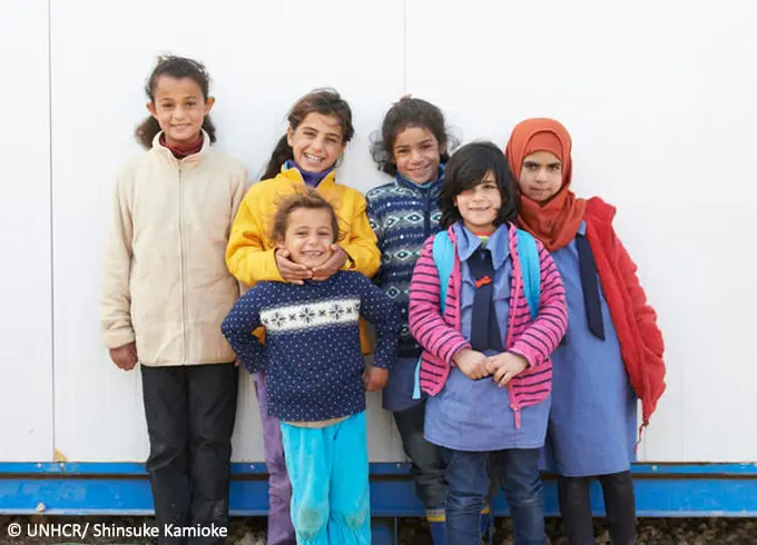 Children pose in front of a wall.