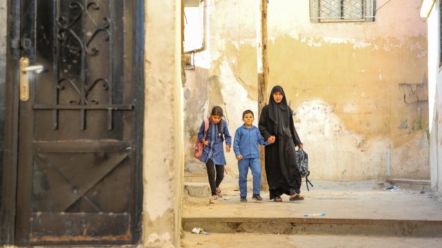 Aisha, 10, and Ahmed, 8, walk home with their aunt Huda.