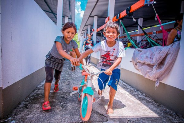 Venezuelan refugee children play with a bike at a shelter in Manaus, Brazil.