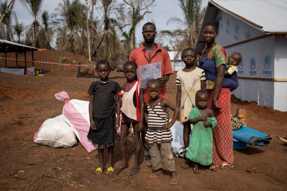 A family poses in front of their shelter.