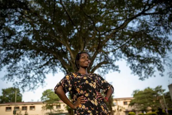 Une jeune femme pose dehors.