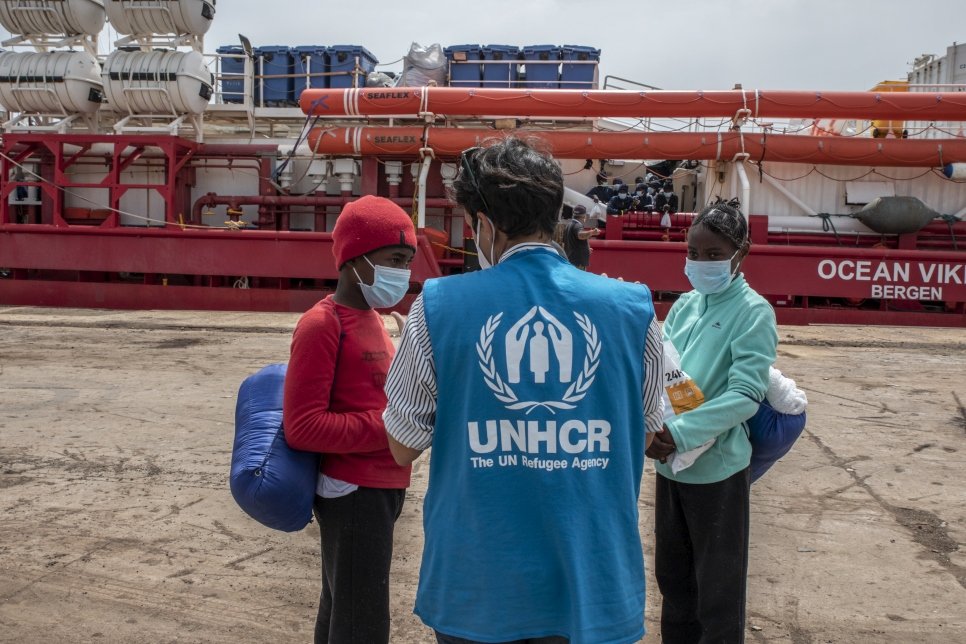 Un employé du HCR s’entretient avec des réfugiés et des migrants qui viennent de débarquer au port d’Augusta, en Sicile, le 1er mai 2021.