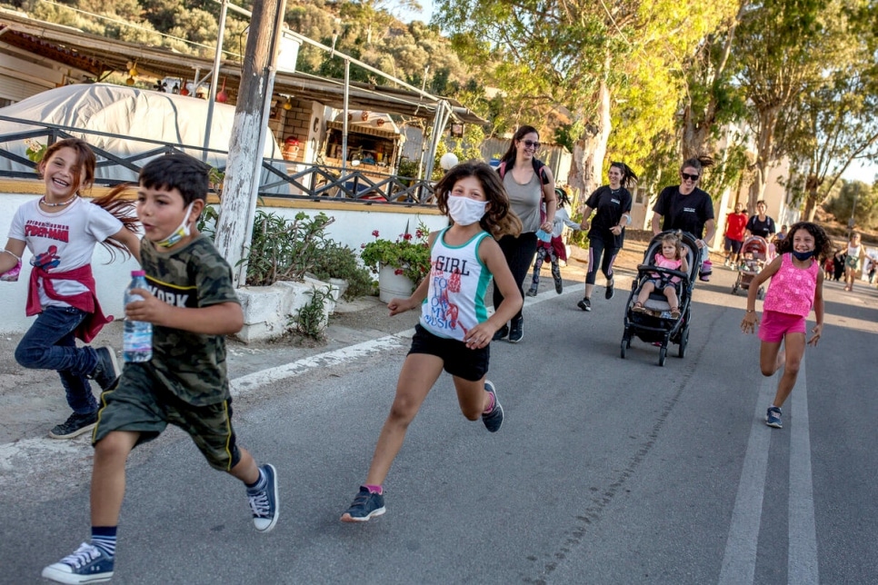 Children and adults run during a short distance marathon during a World Refugee Day event held on the Greek island of Leros