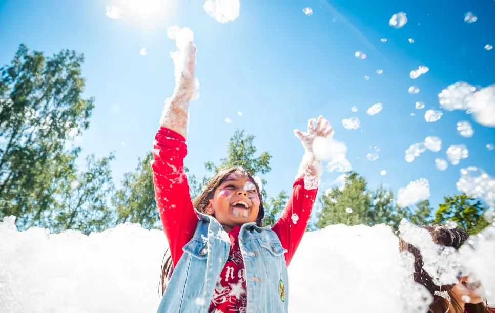 A young refugee enjoys a foam party during World Refugee Day celebrations at a refugee reception centre in Rukla, Lithuania
