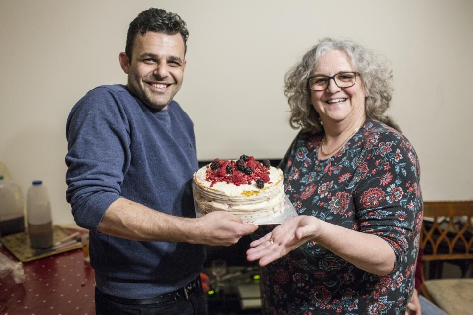 Hani Arnout, 34, originally from Syria, accepts a cake from local resident Helen Stoneman at his home in Ottery St Mary, Devon, UK, in March 2019