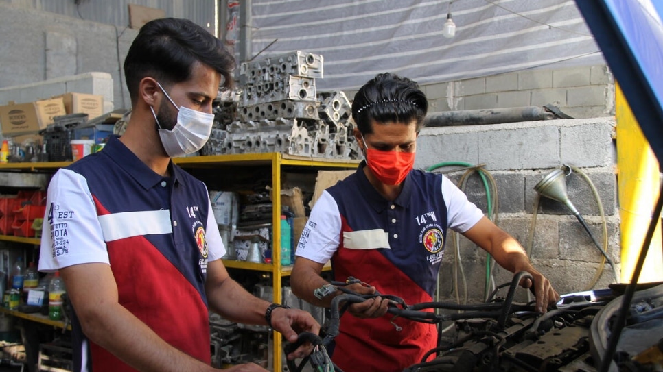 Two men work on a car in their auto-repair shop in Shiraz, Iran.