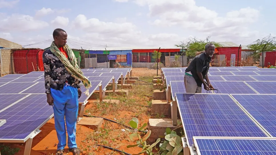 Two men near a solar mini-grid in Buramino Refugee Camp