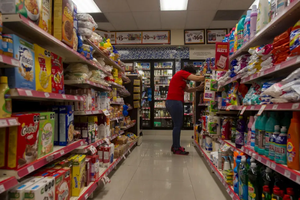 A Salvadoran refugee stacks shelves at a convenience store.