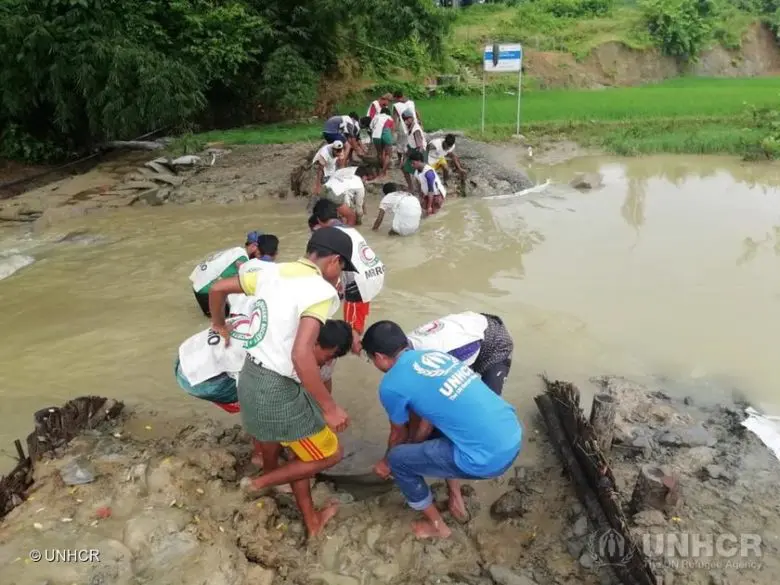 Rohingya refugees cross a river.