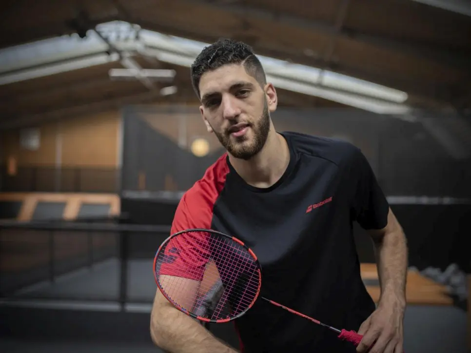 Syrian badminton player poses with racket.