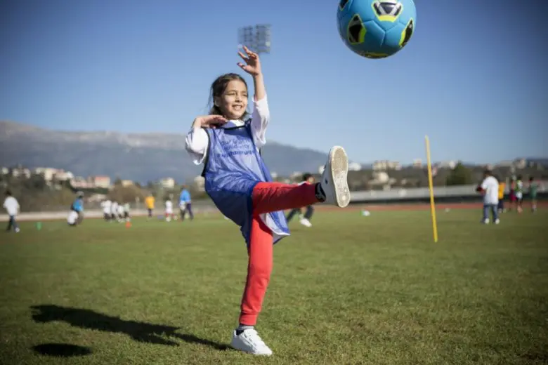 Young girl kicks ball during a refugee solidarity event. National football associations across Europe are stepping up to help welcome refugees into their new communities