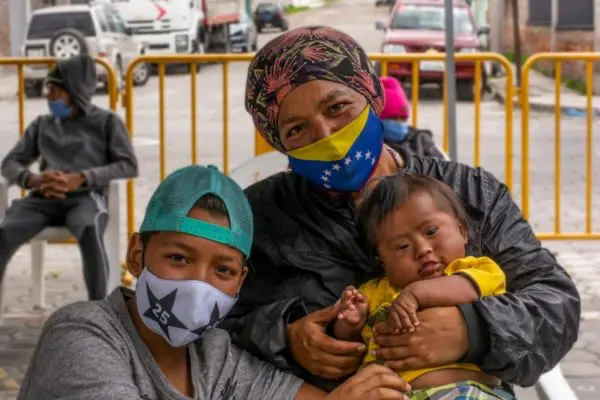 A mother and two children pose outside.