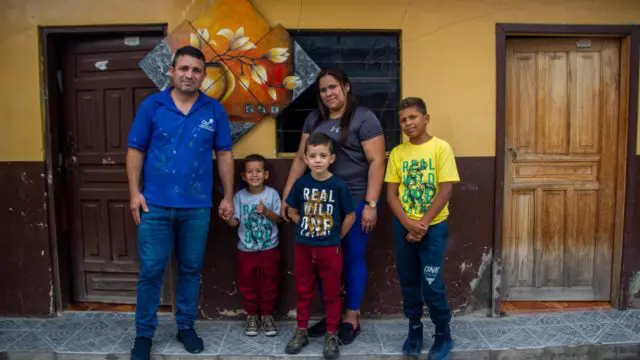 Family poses in front of a home.