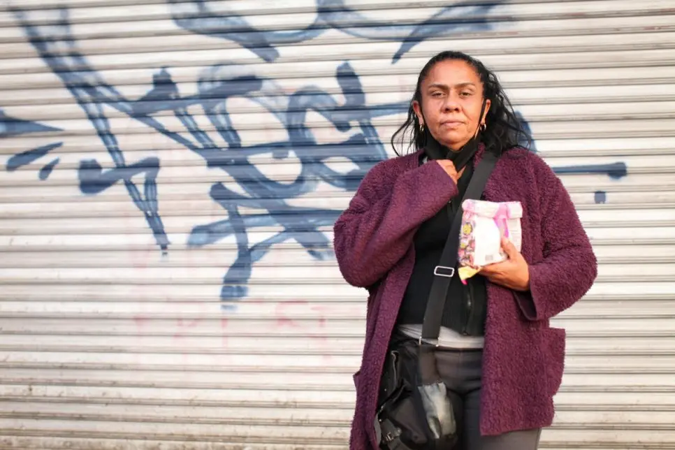 Woman poses in front of a wall.